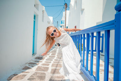 Woman standing on railing against white wall