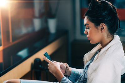 Young woman using mobile phone in salon