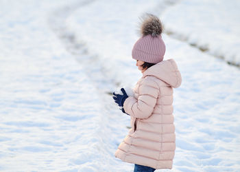 Young girl making a snow ball in a field covered with snow