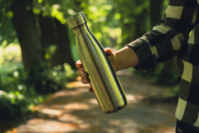 Close-up of unrecognizable female hand holding water bottle. reusable steel thermo water bottle in