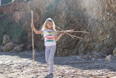 Full length of girl holding sticks while walking at beach