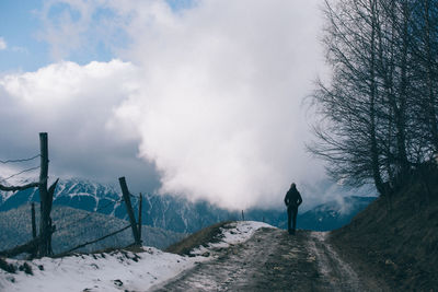 Rear view of woman walking on road during winter