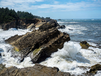 Rock formations on shore against sky