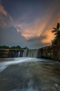 Scenic view of waterfall against sky during sunset