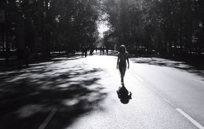 Rear view of woman walking on road in city