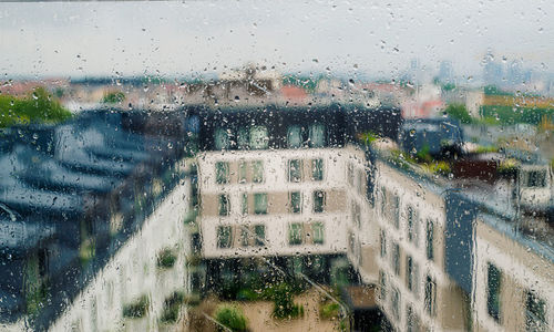 Buildings seen through wet glass window during rainy season