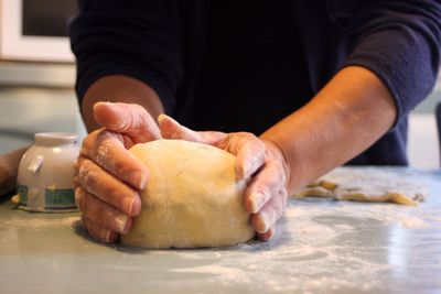 Midsection of woman kneading dough on table