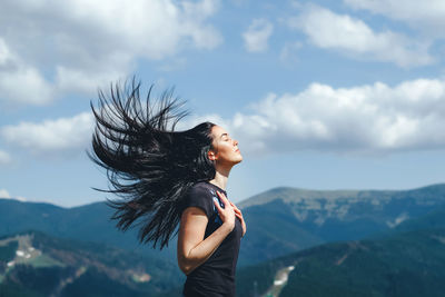 Woman standing on mountain against sky