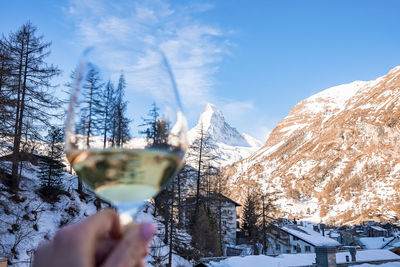 Woman holding wineglass with matterhorn mountains and snowy town in background