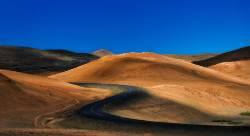 Scenic view of desert against clear blue sky