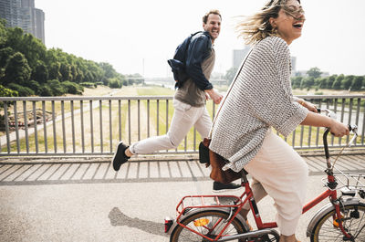 Happy couple crossing a bridge with bicycle and by foot