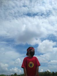 Low angle view of boy standing against sky