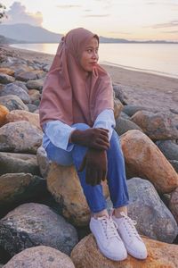 Woman sitting on rock at beach