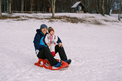 Portrait of smiling young woman skiing on snow covered field