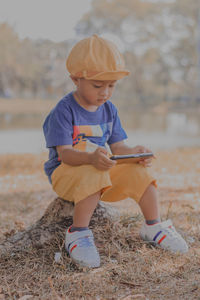Portrait of indonesian little boy sitting on field