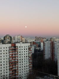 Buildings in city against clear sky during sunset