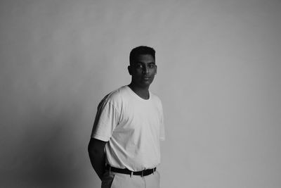 Portrait of young man standing against wall