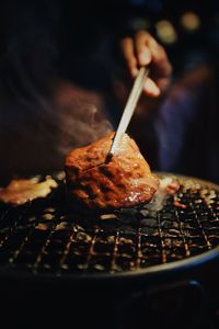 Close-up of person hand roasting meat on barbecue grill