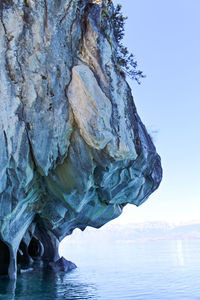 Rock formation in sea against clear sky