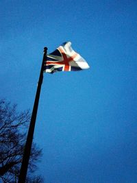 Low angle view of flag against clear blue sky