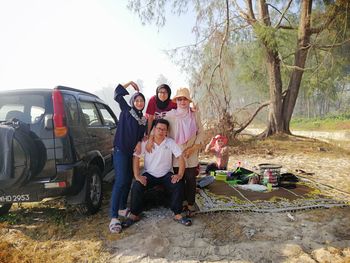 People on land by car against trees