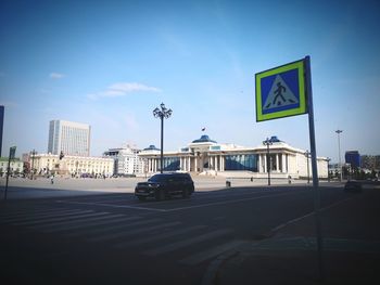 Road sign on city street against sky