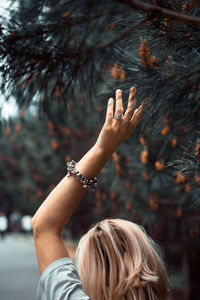 Rear view of woman touching tree