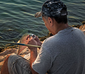 Rear view of man sitting by lake