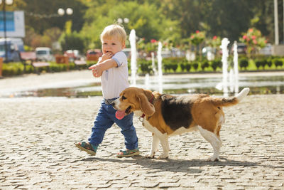 Cute boy with dog standing on street