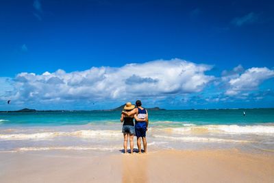 Full length of friends standing on shore at beach