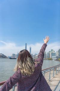 Rear view of woman walking in water against sky