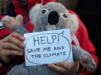 Close-up of hand holding stuffed toy and note