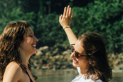 Close-up of smiling young woman against trees