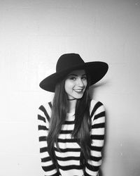 Portrait of smiling young woman standing against white wall