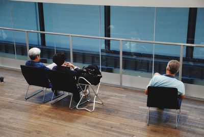 Rear view of people sitting on table by sea