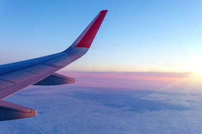 Airplane flying over sea against sky during sunset