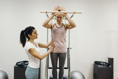 Fitness instructor assisting woman doing pilates in studio