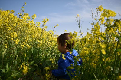 Baby with yellow flowers on field