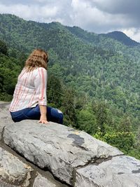 Man sitting on rock looking at mountains