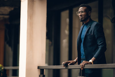 Full length of young man standing against railing