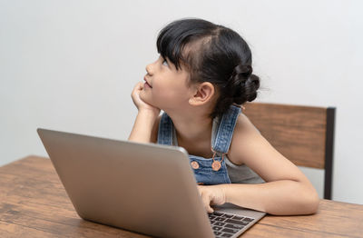 Boy looking away while sitting on table