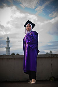 Portrait of a smiling young woman standing against sky