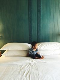 High angle view of baby boy sitting on bed at home