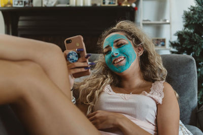 Portrait of woman using mobile phone while sitting on sofa