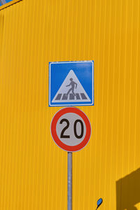 Vertical frame, traffic signs on against a bright yellow warehouse wall 