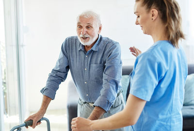 Nurse assisting man in walking at home