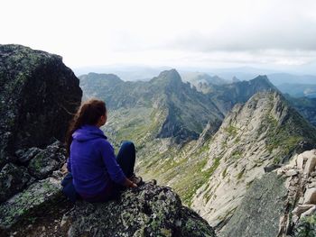 Rear view of woman looking at mountains against sky