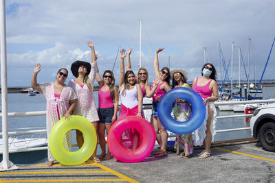 Women standing with their arms up in a bikini with beach accessories. 