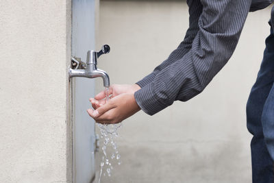 Close-up of hands holding water running from tap