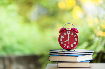 Close-up of stacked books and alarm clock at home